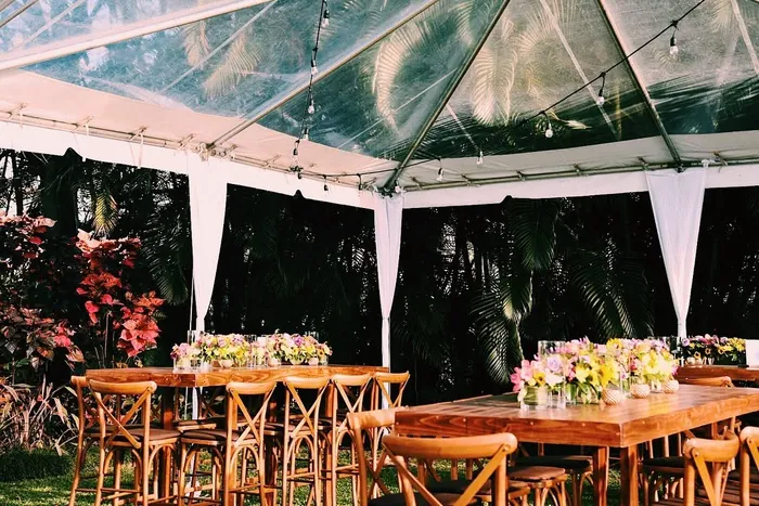Mesas de madera con flores amarillas y rosadas bajo la carpa