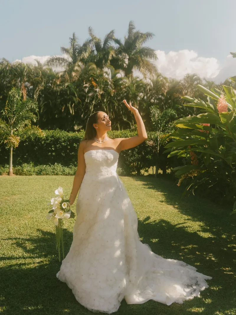 Novia en el jardín con su ramo, saludando con la mano